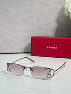 Eyeglasses by Prada with light pink lenses and silver frame, studded detailing on hinges