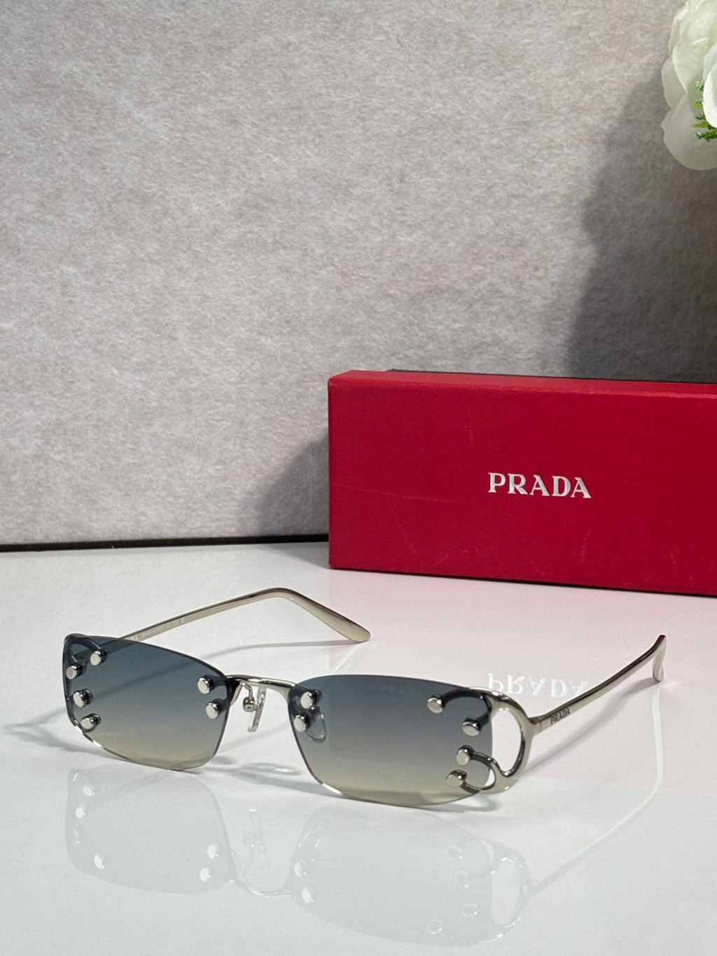 Eyeglasses by Prada with pale green lenses and silver frame, studded accents at temples
