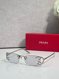 Eyeglasses by Prada with silver frame and clear lenses, studded detail at temples