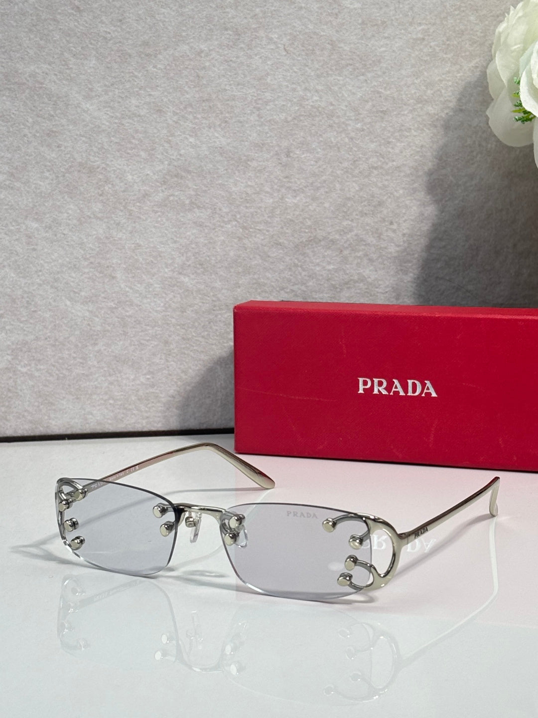 Eyeglasses by Prada with silver frame and clear lenses, studded detail at temples