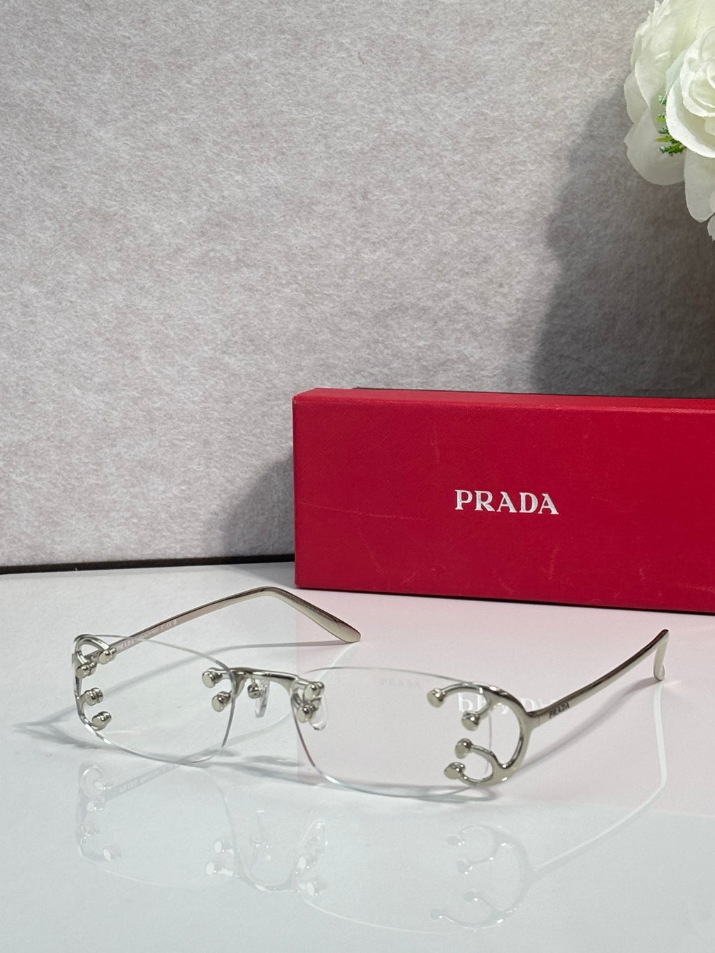 Eyeglasses by Prada with silver frame and clear lenses, decorative studs on bridge
