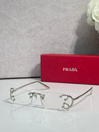 Eyeglasses by Prada with silver frame and clear lenses, decorative studs on bridge