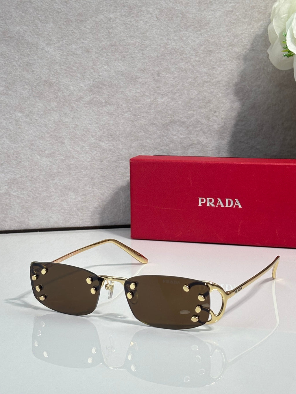 Eyeglasses by Prada with dark tint lenses and gold-tone frame, studded accents on temples