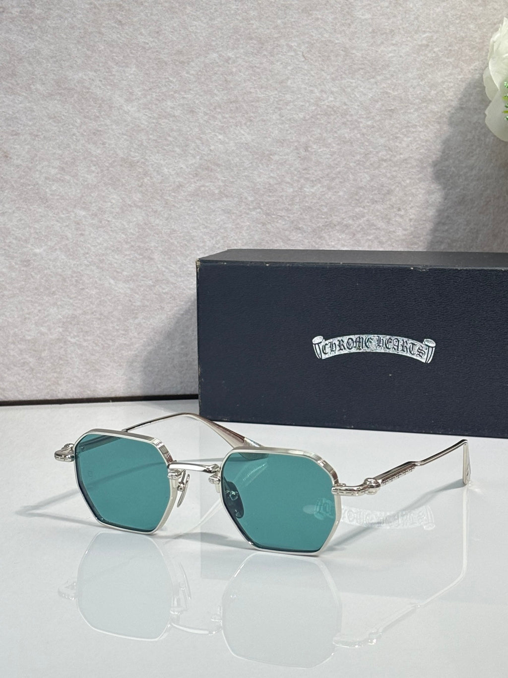 Chrome sunglasses with teal square lenses and silver frame, front view
