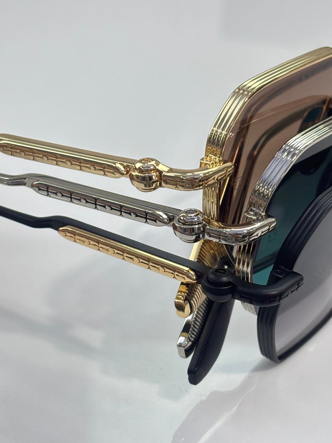 Chrome sunglasses close-up of gold-toned hinges and temple, dark lens edge