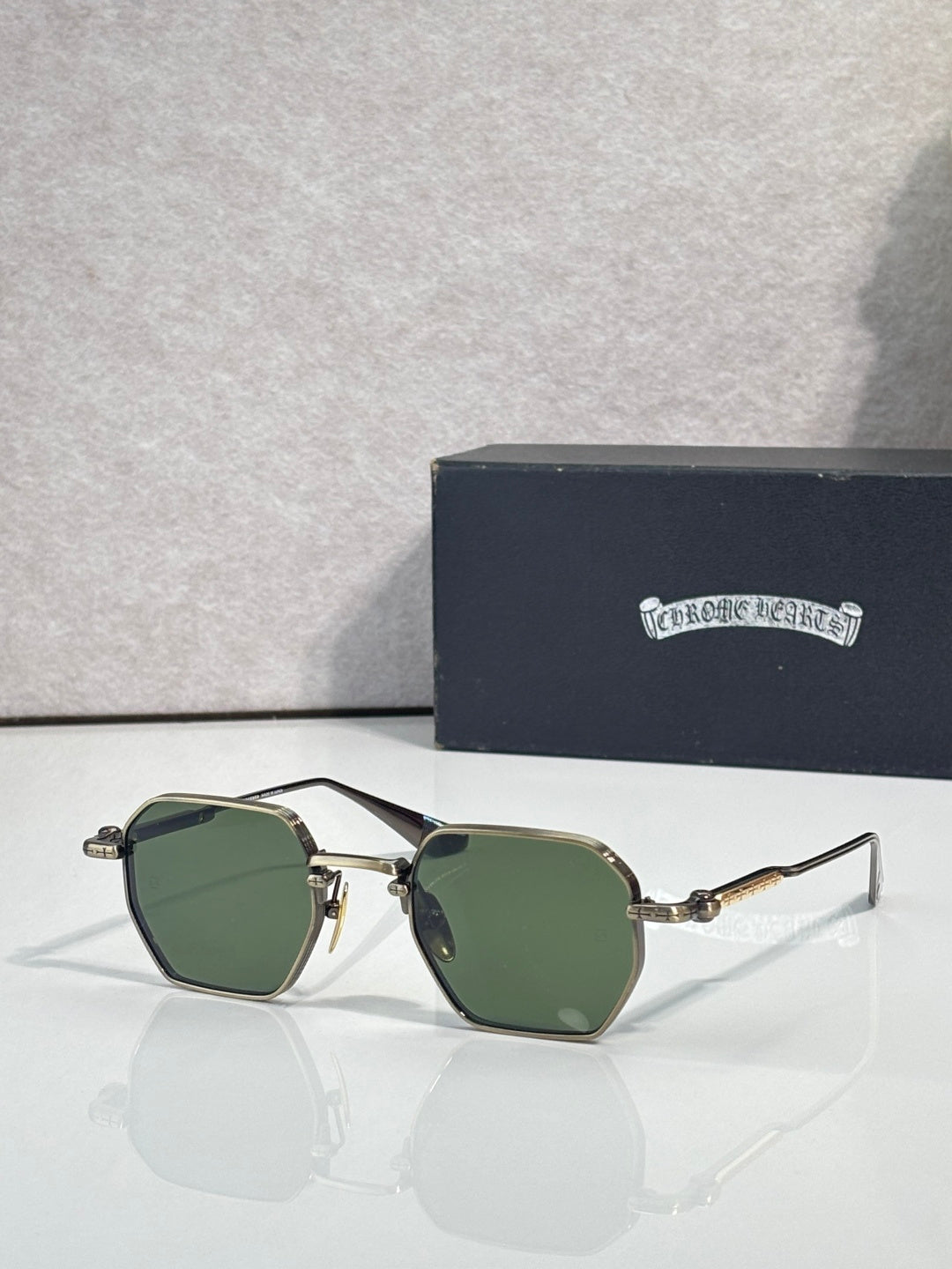 Chrome sunglasses with green lenses and gold-toned frame, front view