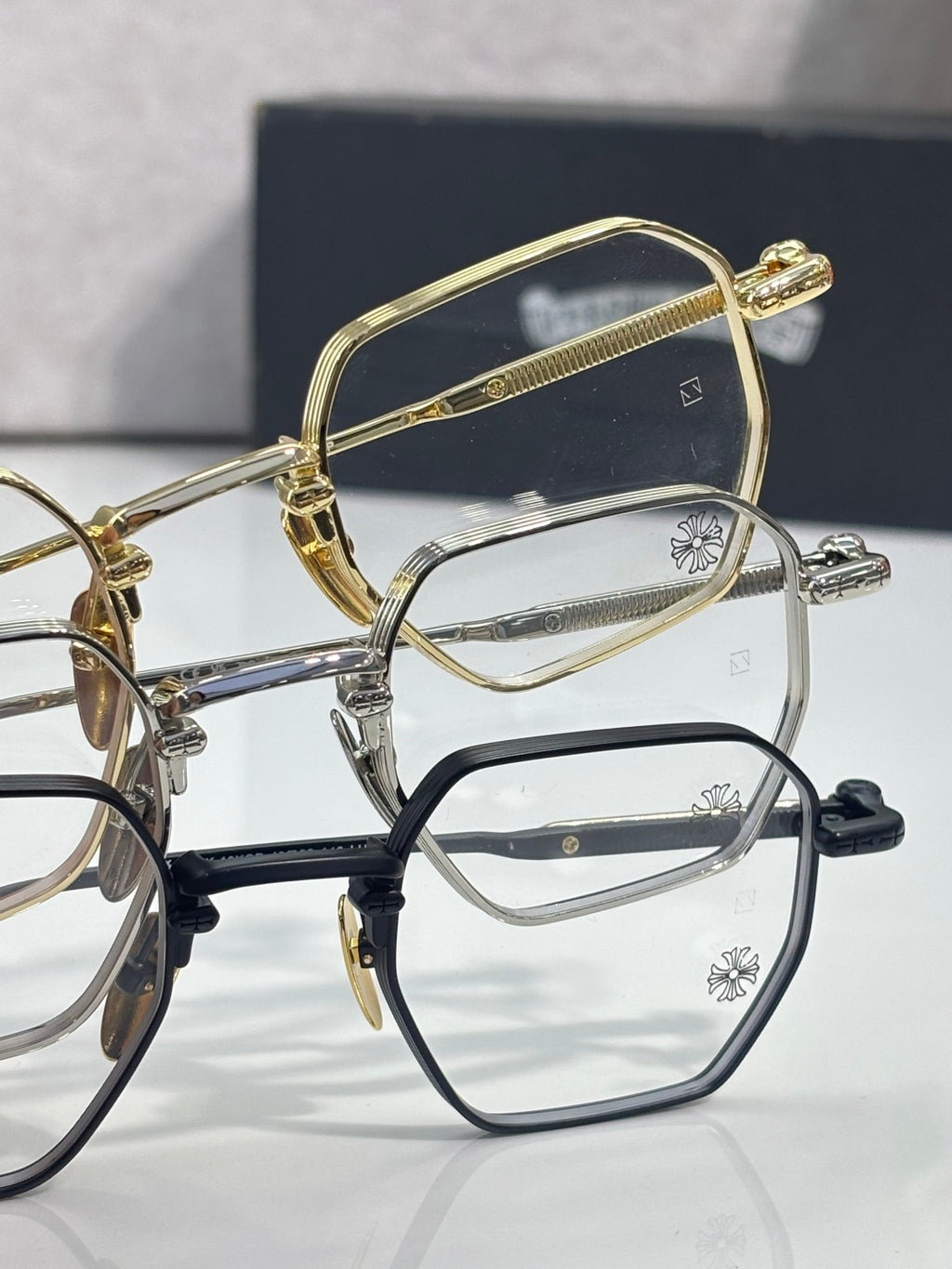Gold, silver, and black eyeglasses with clear rectangular lenses
