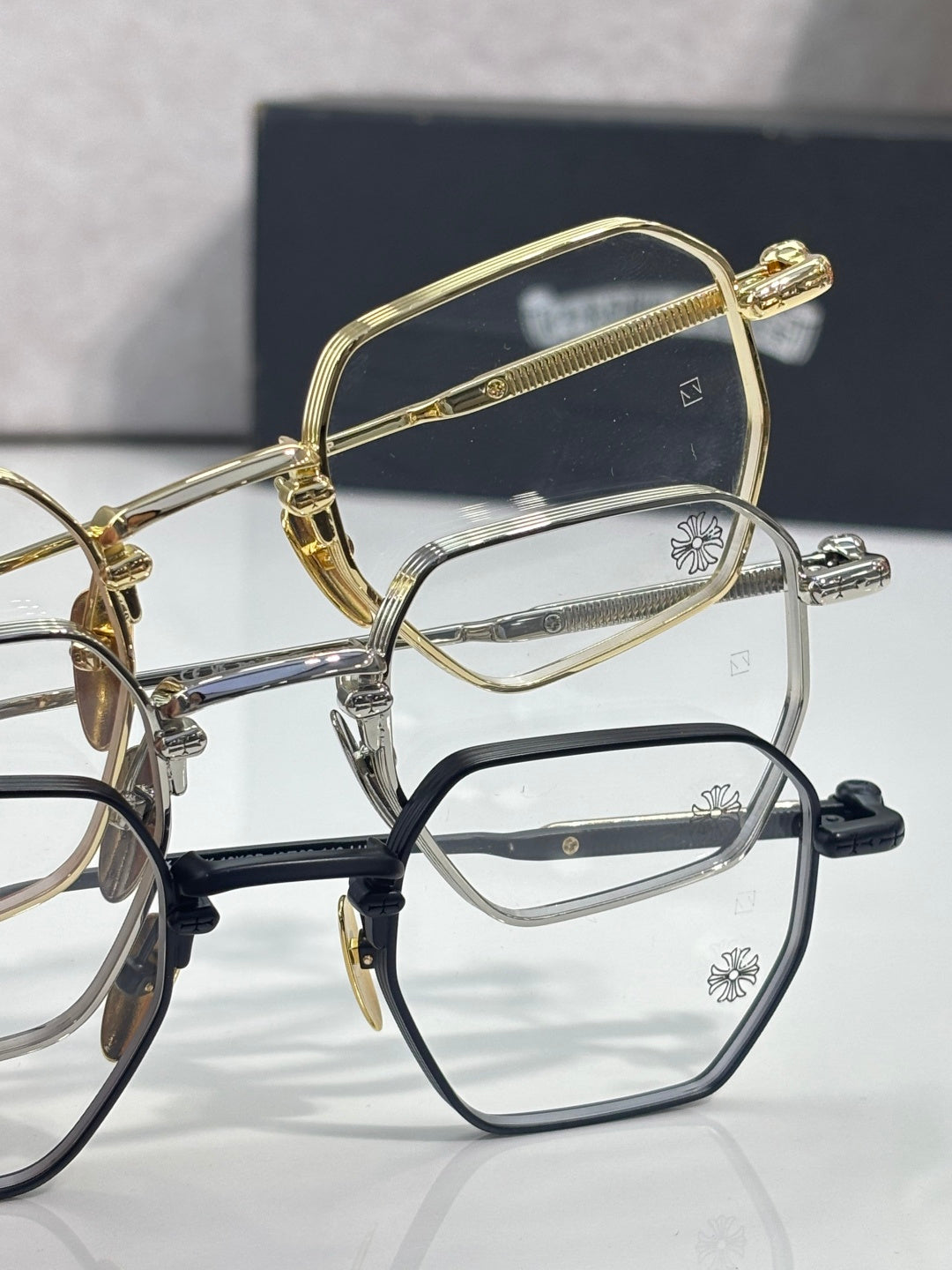 Gold, silver, and black eyeglasses with clear rectangular lenses