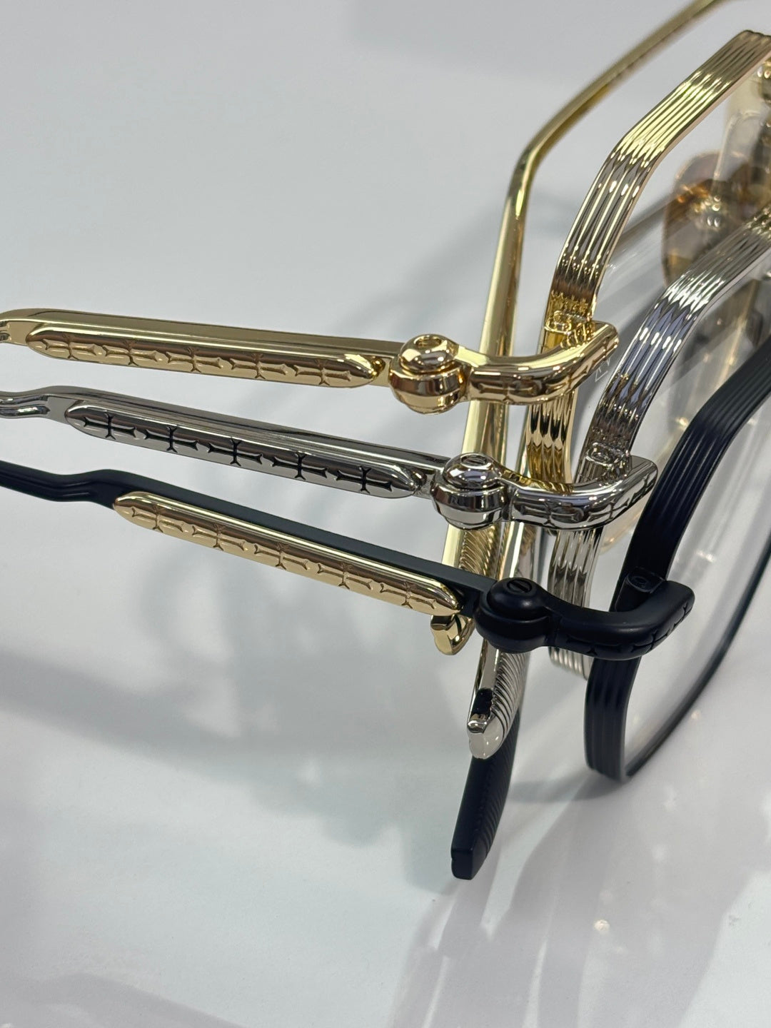 Gold and black eyeglass temples close-up with metal hinges and clear lens