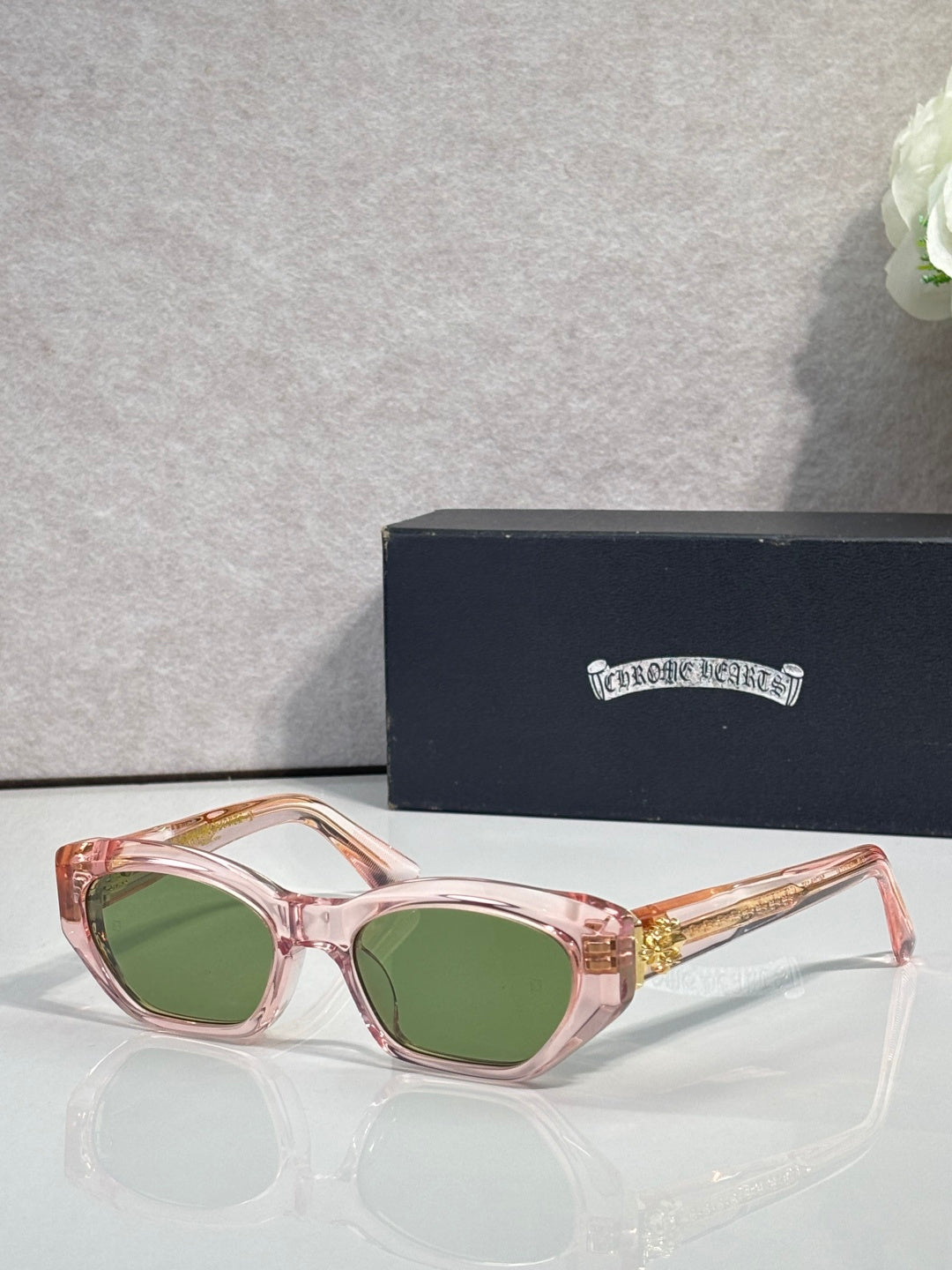 Pink and clear glasses with green lenses and gold-toned metal temples