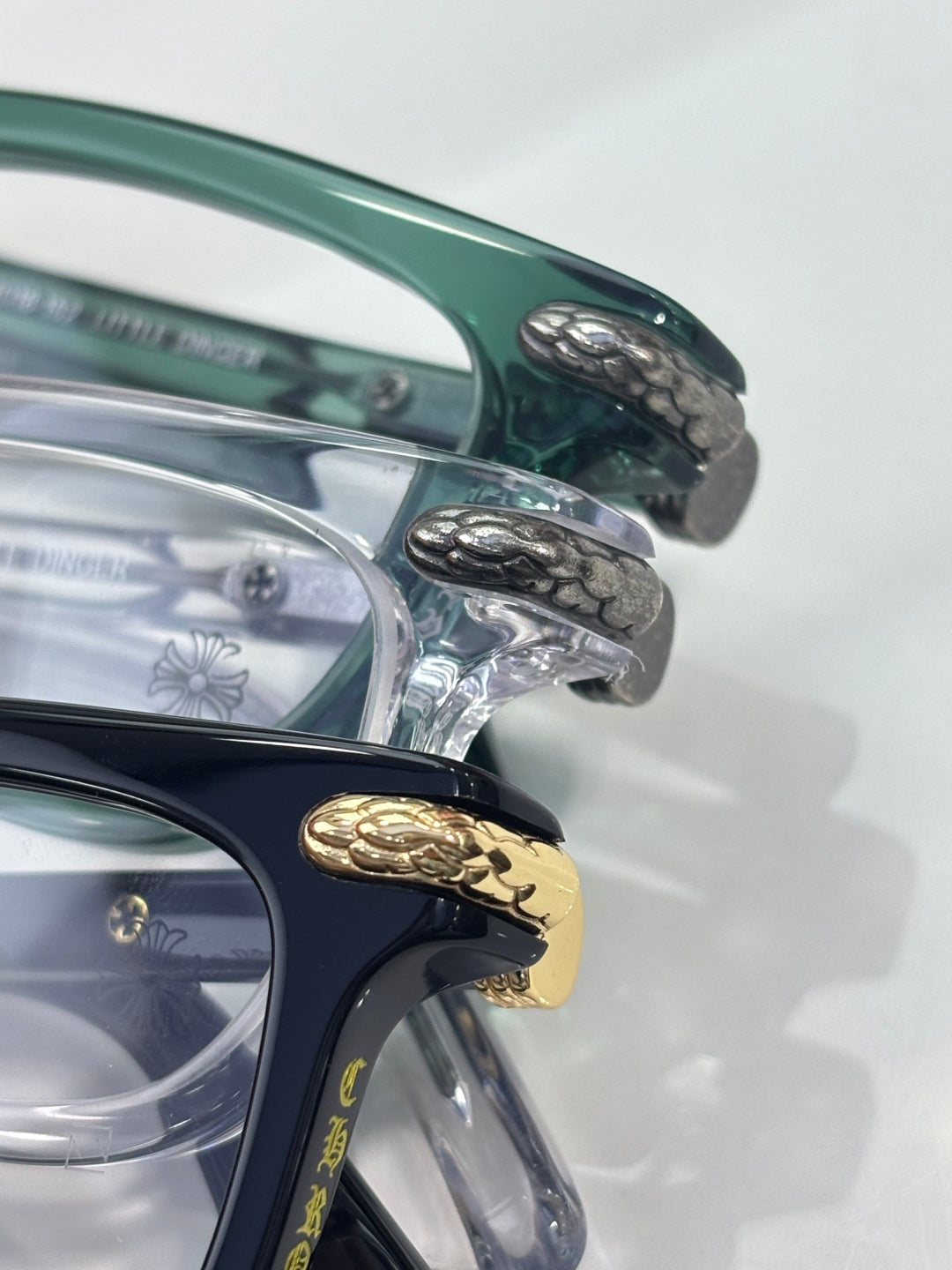 Chrome eyeglasses close-up: teal temple with engraved gold and silver details