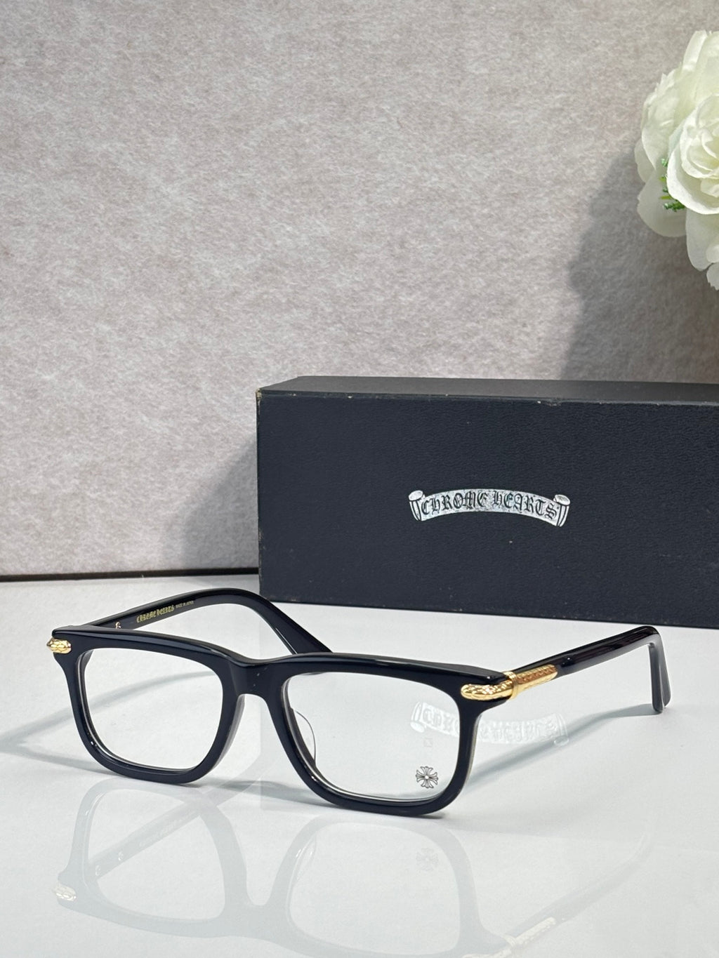 Chrome eyeglasses with dark frame and gold temple accents, clear lenses