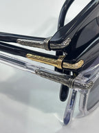 Dark blue eyeglasses close-up with gold hinge detail and clear temple