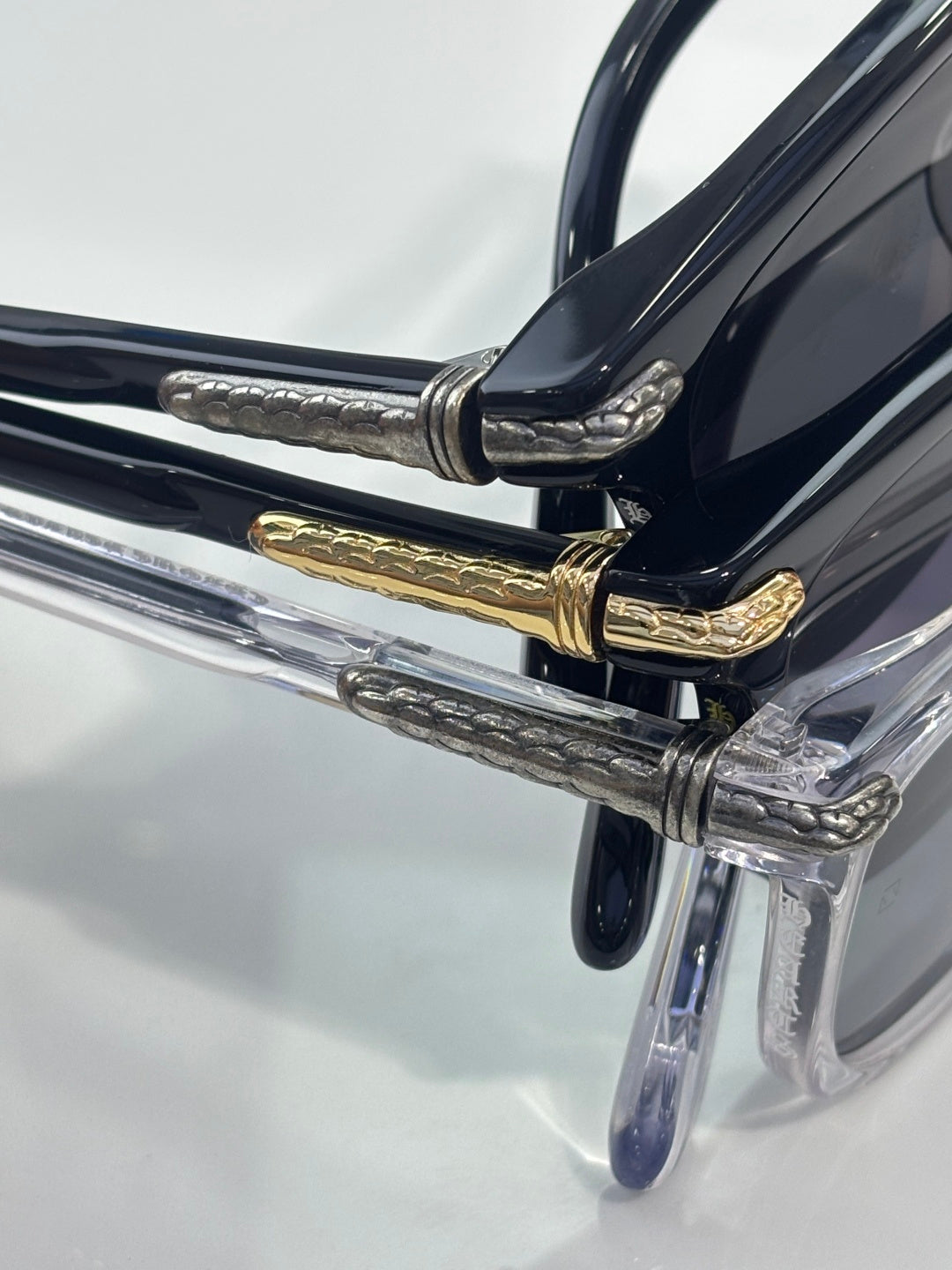 Dark blue eyeglasses close-up with gold hinge detail and clear temple