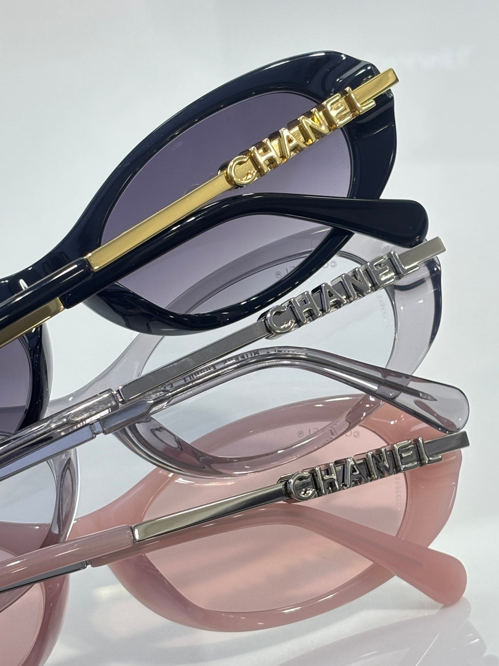 Chanel sunglasses close-up: dark and light frames with Chanel logo on metal temple arms