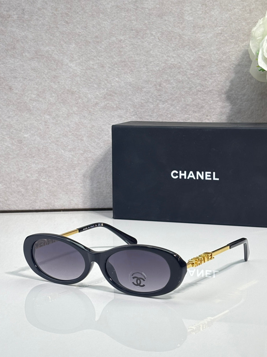 Chanel sunglasses with dark blue frames and gray tinted lenses; gold Chanel logo