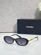 Chanel sunglasses with dark blue frames and gray tinted lenses; gold Chanel logo