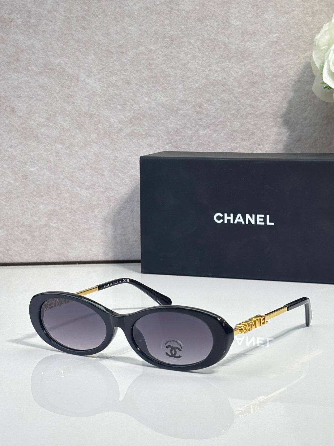 Chanel sunglasses with dark blue frames and gray tinted lenses; gold Chanel logo
