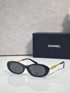 Chanel sunglasses with dark blue frames and gray lenses; gold Chanel logo temple detail