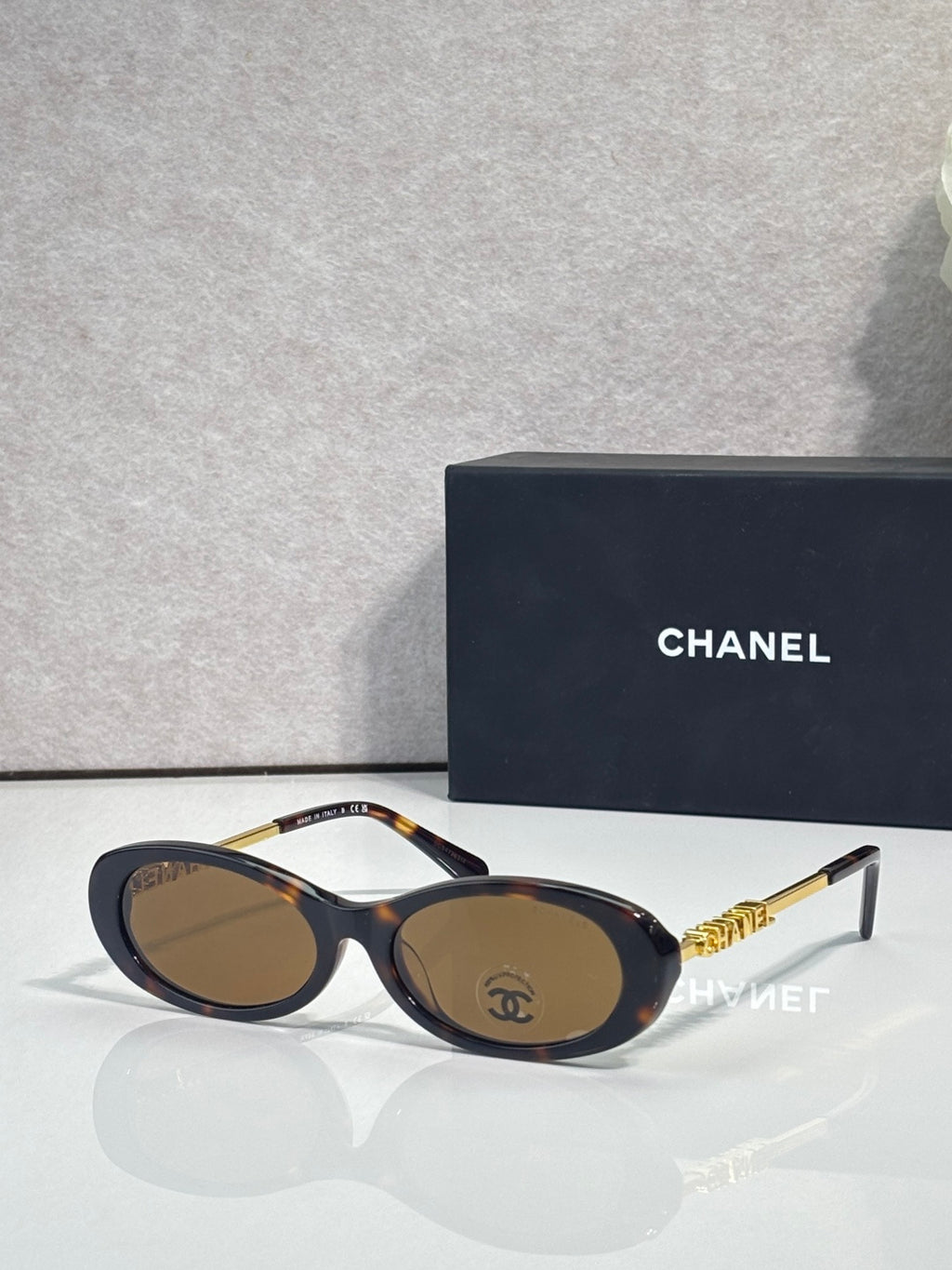 Chanel sunglasses with dark blue frames and brown lenses; gold Chanel logo temple