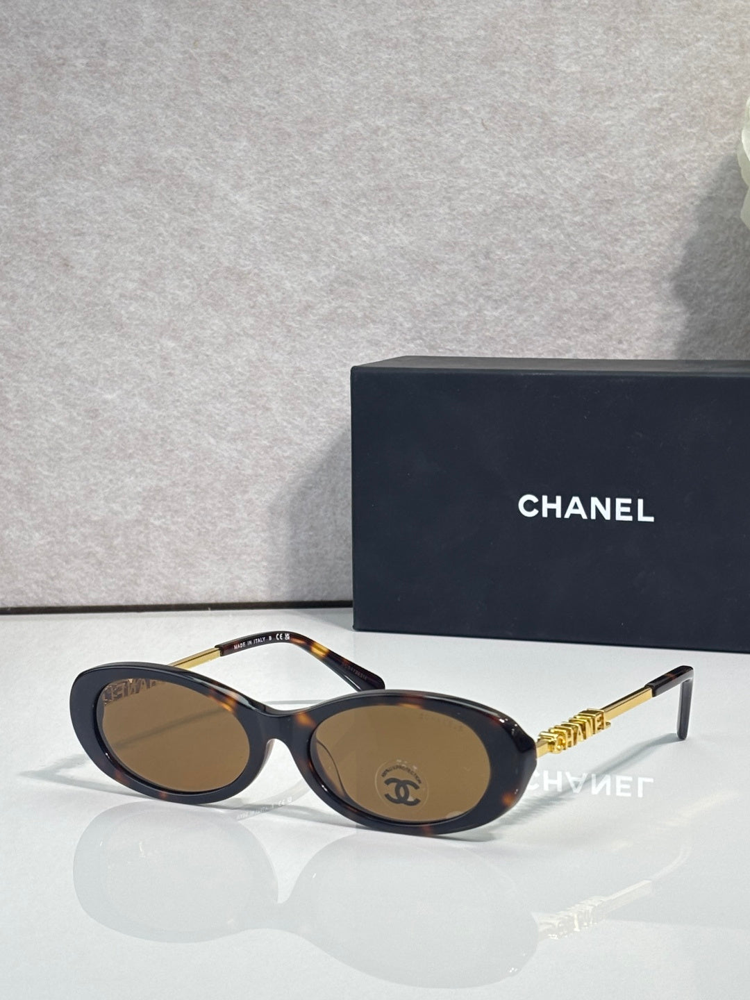 Chanel sunglasses with dark blue frames and brown lenses; gold Chanel logo temple