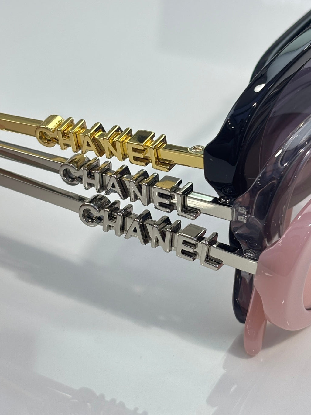 Chanel sunglasses close-up: gold and silver logo accents on temple arms with dark frames