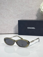 Chanel sunglasses with olive-green frames and dark lenses; Chanel logo on metal temple
