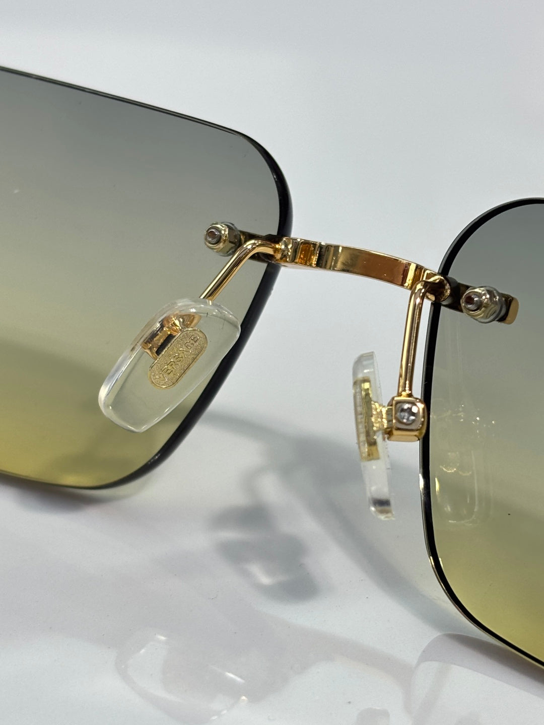 Versace glasses close-up: gold front, dark lens rim, Medusa emblem