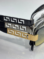 Versace glasses close-up: black temple with gold Greek key band, clear lens