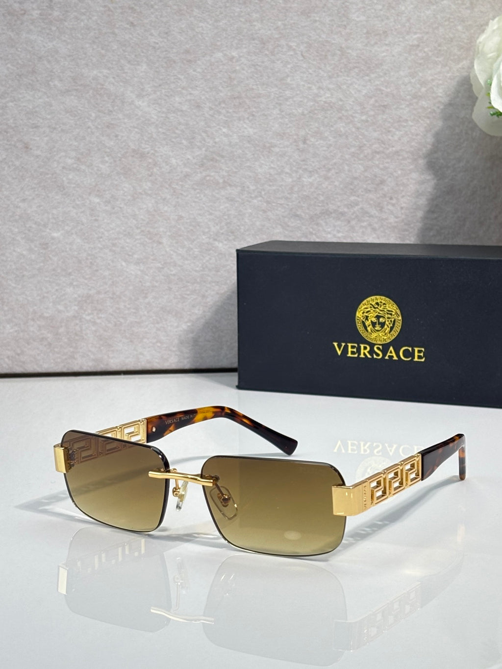 Gold-tone sunglasses with brown tinted lenses and geometric logo temples