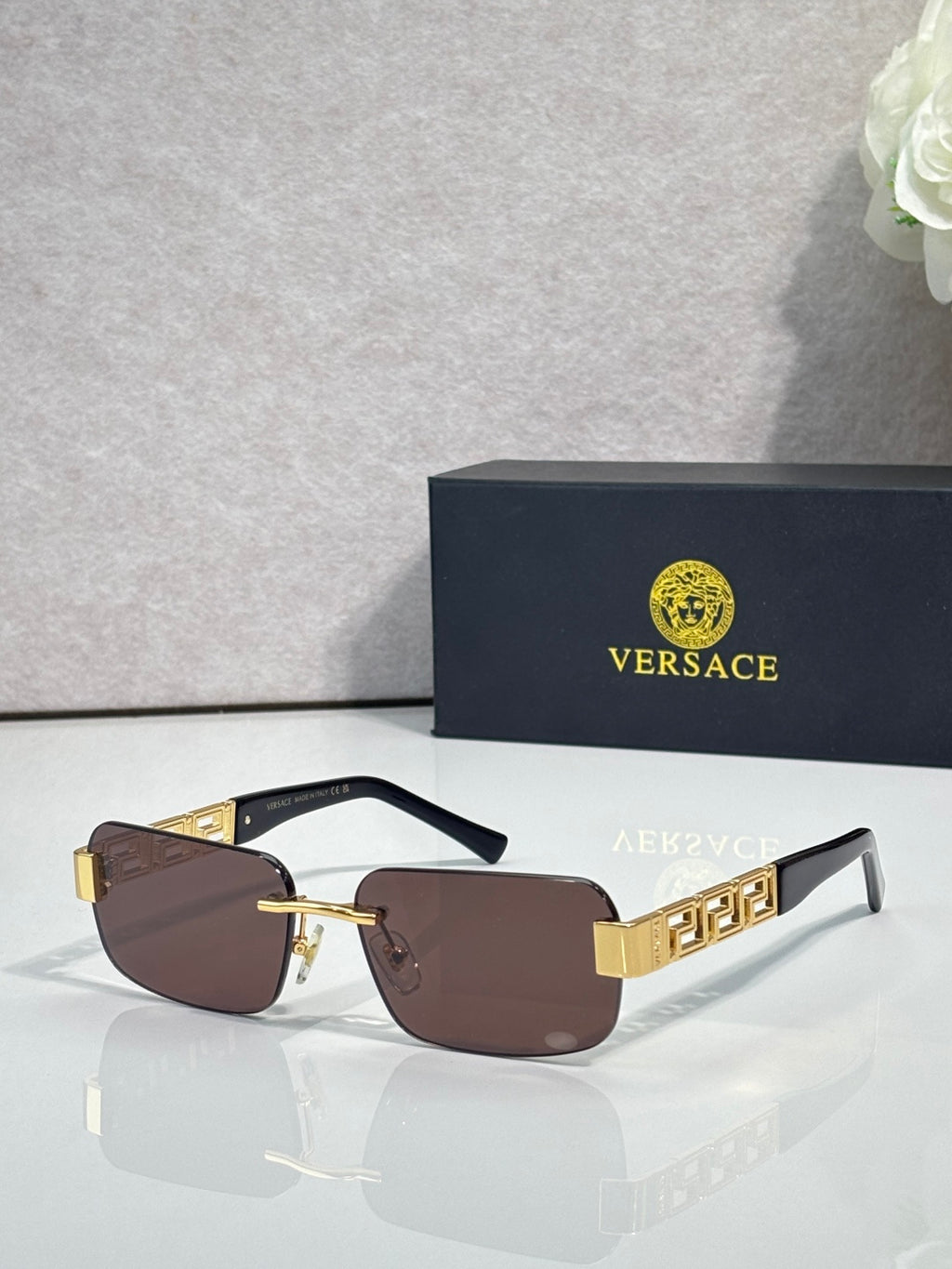 Black-frame sunglasses with brown tinted lenses and gold bar detail