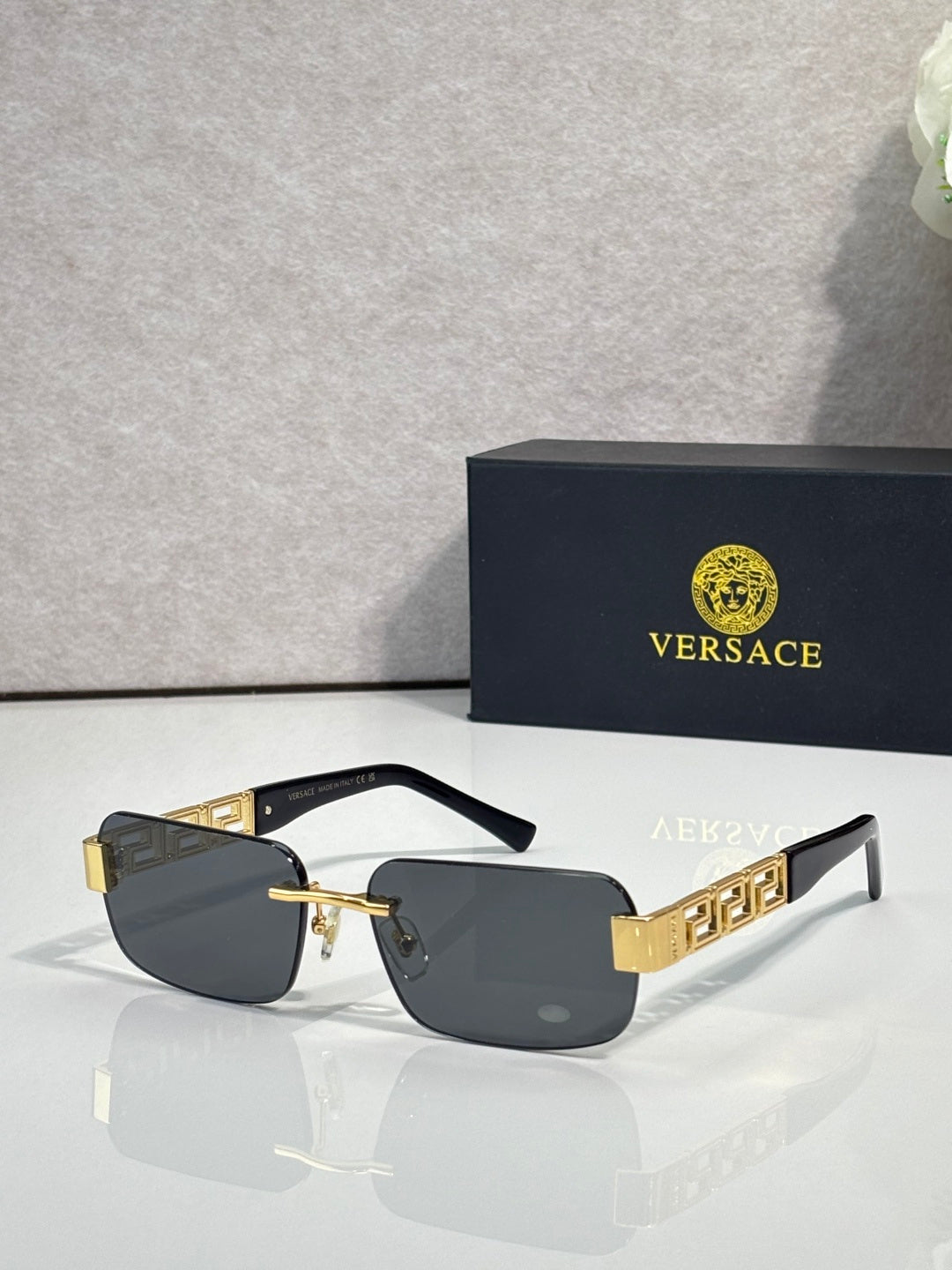 Black-frame sunglasses with dark lenses and gold bar accents