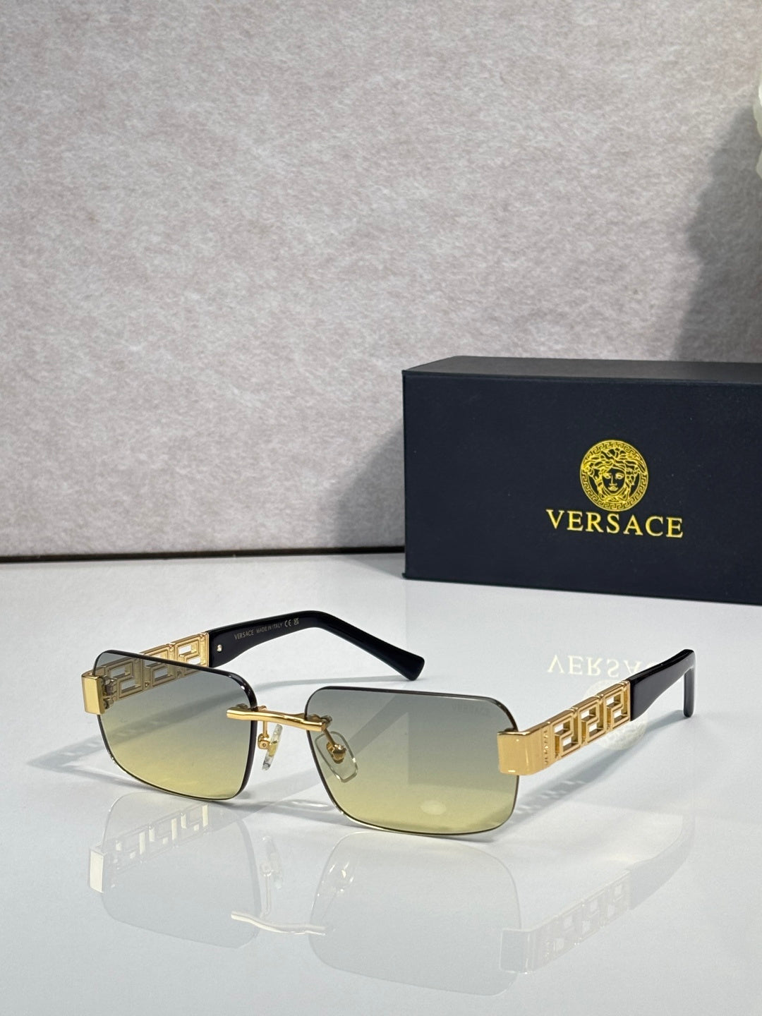 Gold-tone sunglasses with pale yellow tinted lenses and geometric logo temples