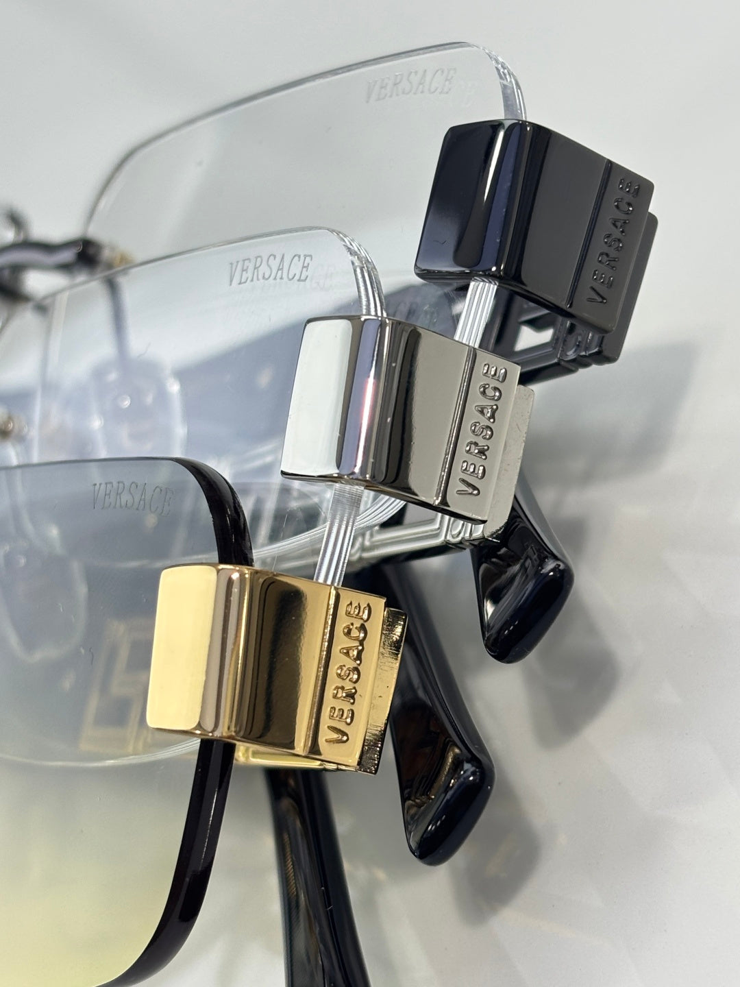 Metal sunglasses with clear lenses, gold and black hinges, geometric temple detail