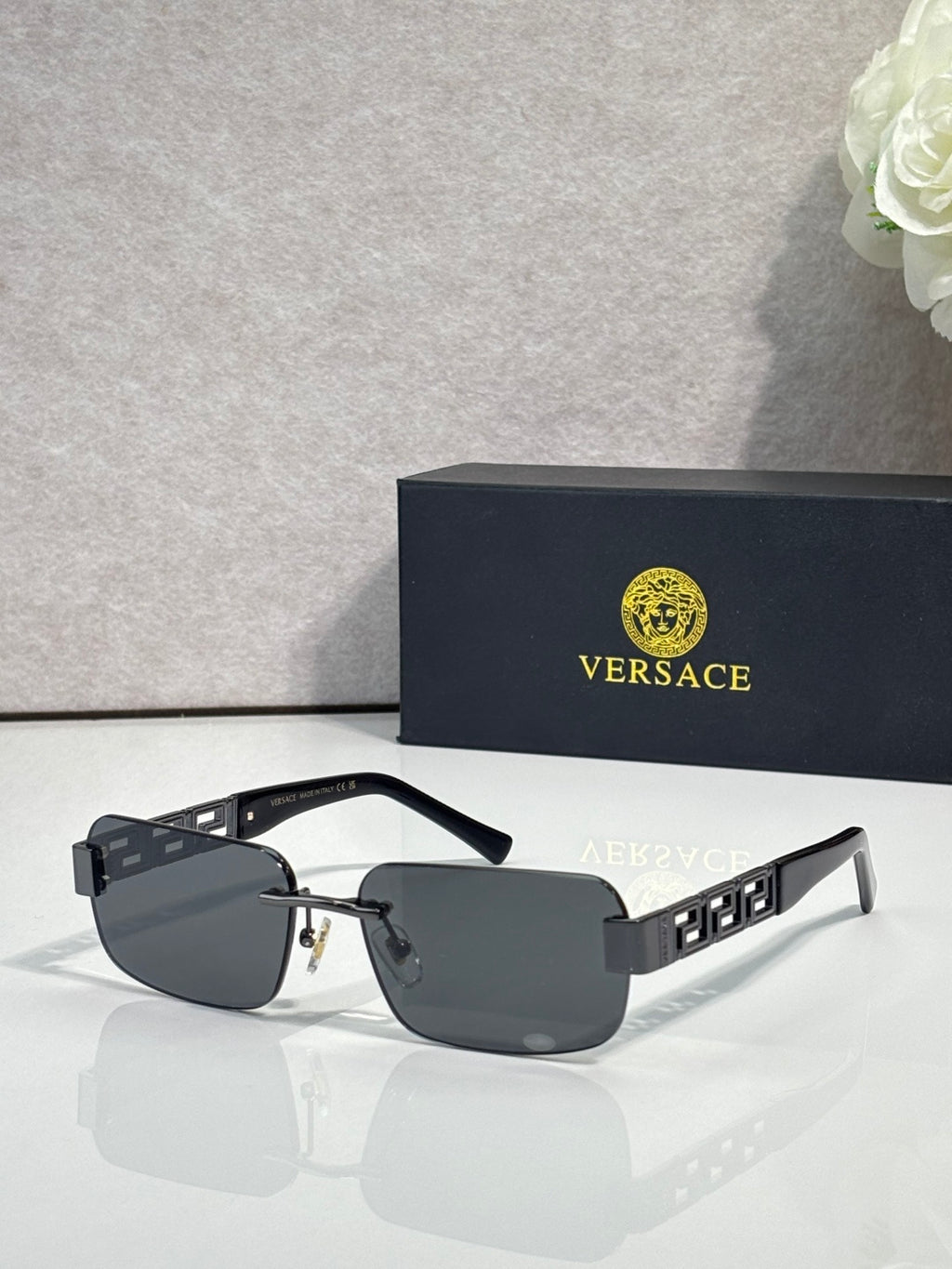 Black-frame sunglasses with dark gray tinted lenses and gold bar detail