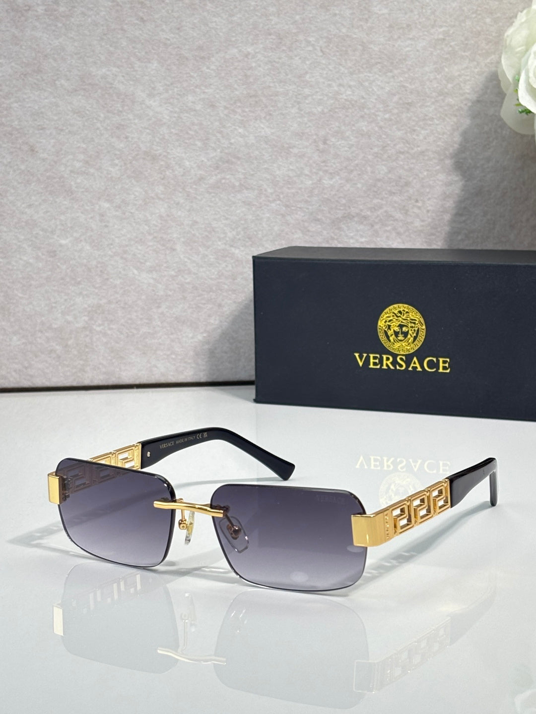 Black-frame sunglasses with light purple tinted lenses and gold bar detail
