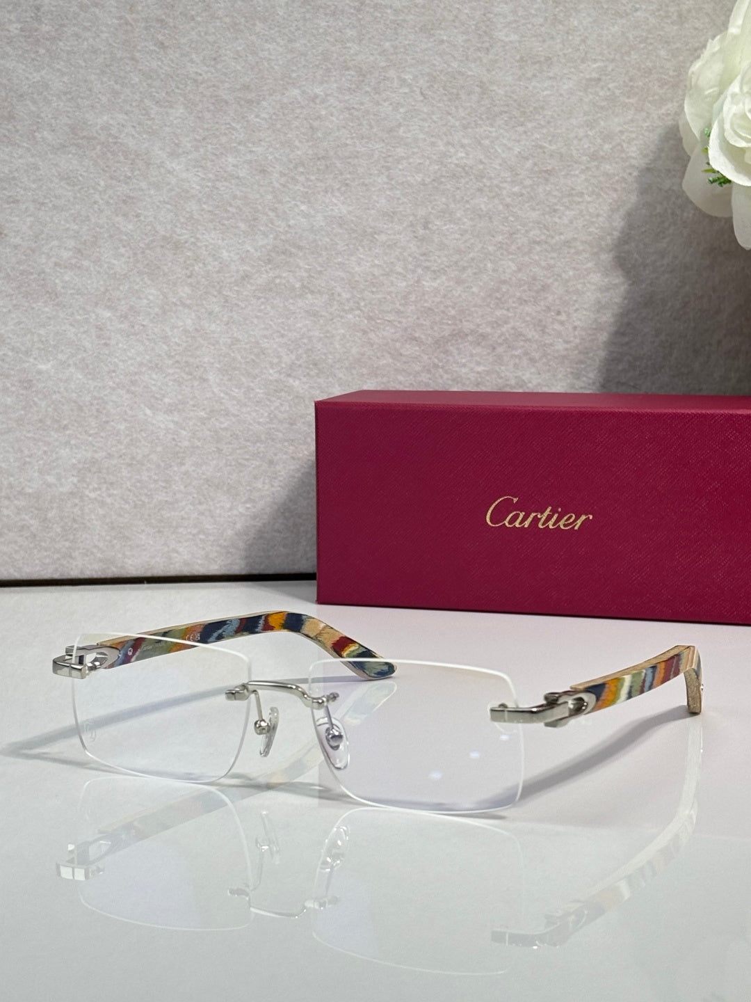 Cartier glasses with clear lenses, gold frame, and multicolor striped temples