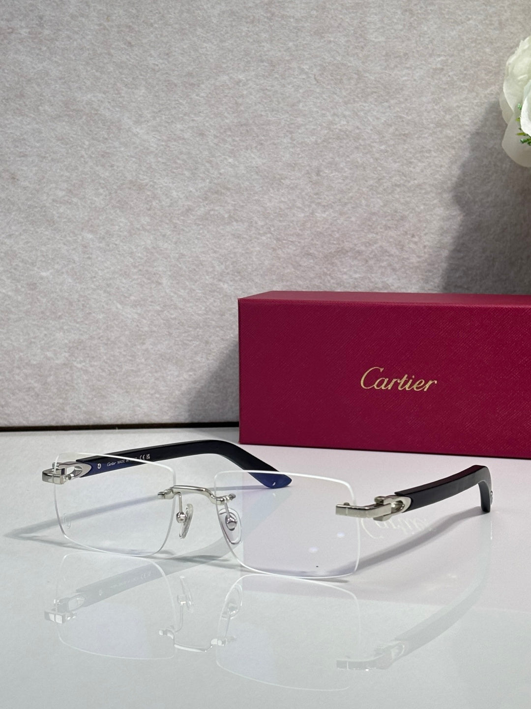 Cartier glasses with clear lenses, gold frame, and blue-accent temples