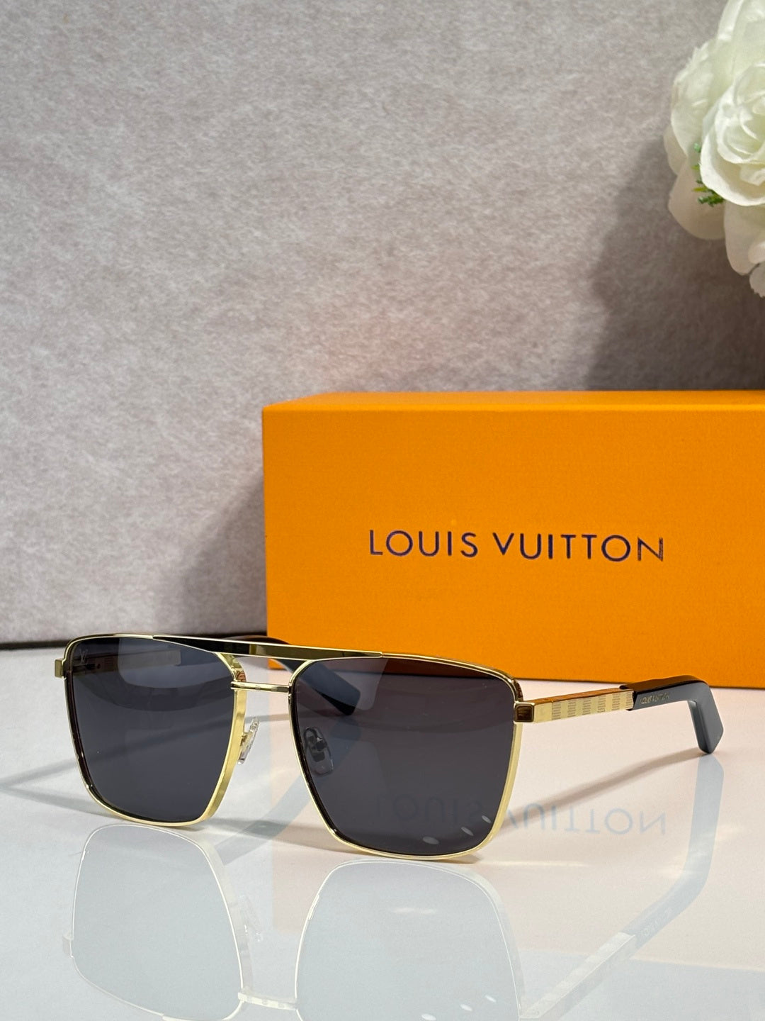 Louis Vuitton sunglasses with dark tinted lenses and black frame, gold-tone details