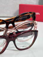 Prada reddish-brown eyeglasses close-up with PRADA Milano branding on temple
