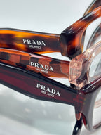 Prada Milano orange-brown eyeglasses close-up showing PRADA and Milano on frame