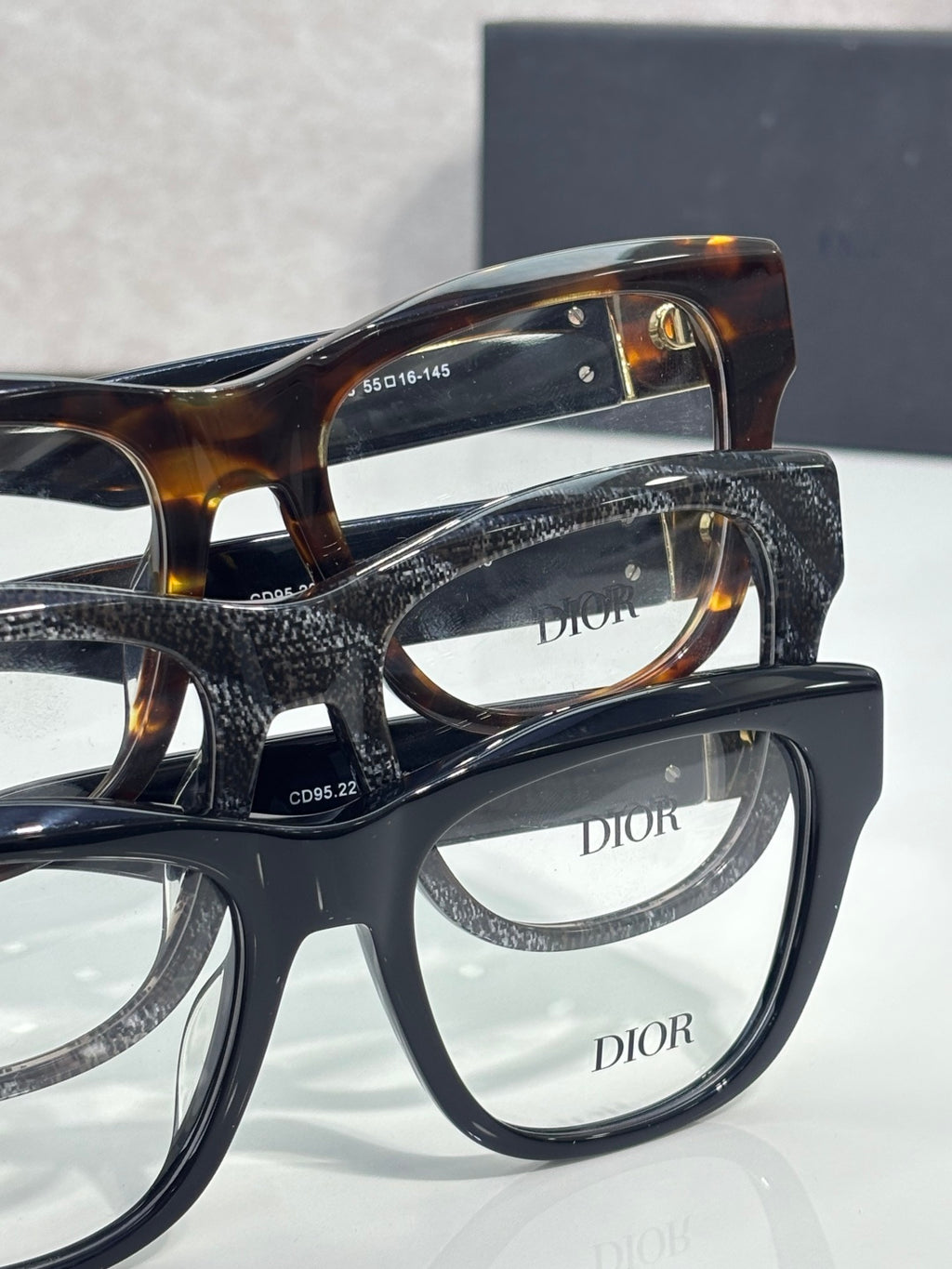 Stacked eyeglasses with navy frames and clear lenses, DIOR logos visible