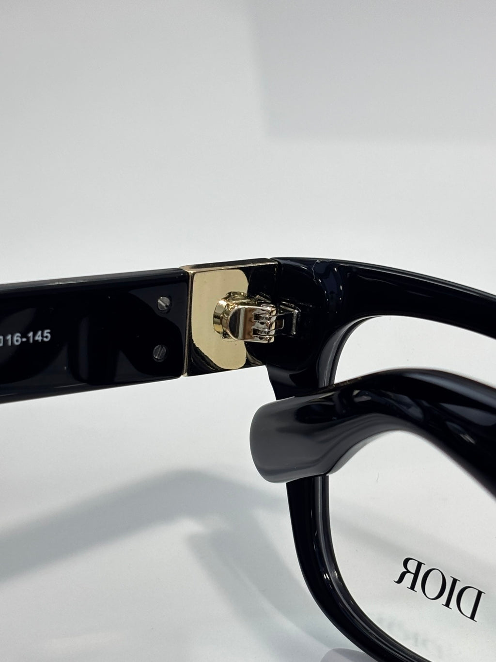 Black eyeglass frame close-up with metal hinge and DIOR logo on lens