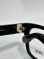 Black eyeglass frame close-up with metal hinge and DIOR logo on lens
