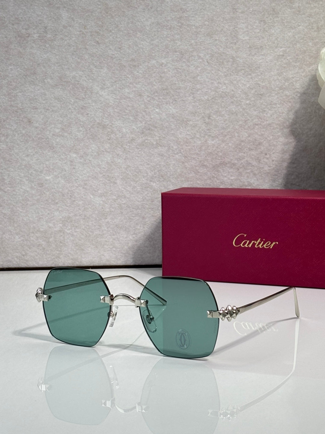 Silver metal-frame glasses with teal tinted lenses and small jeweled hinge hardware