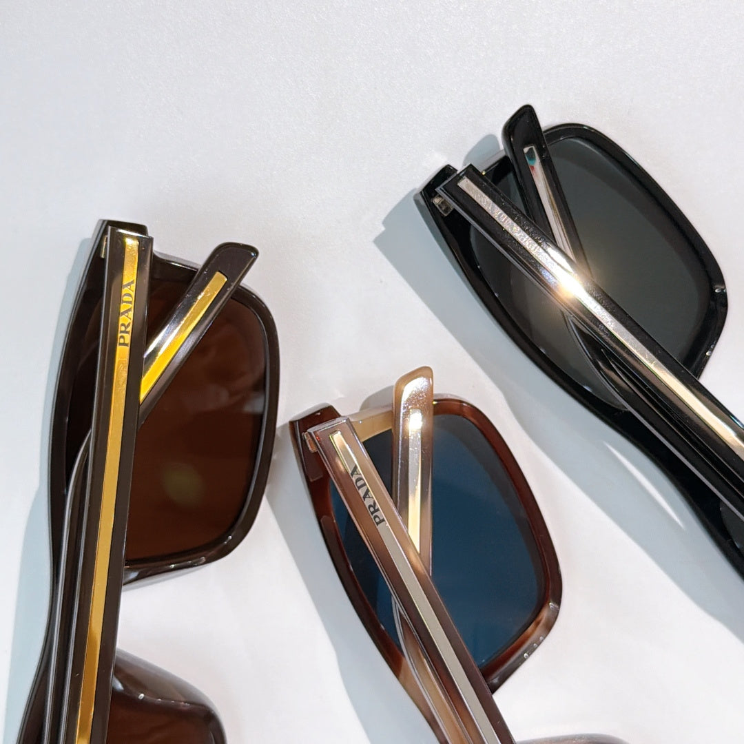 Prada sunglasses close-up: black and brown frames with mirrored lenses and gold trim