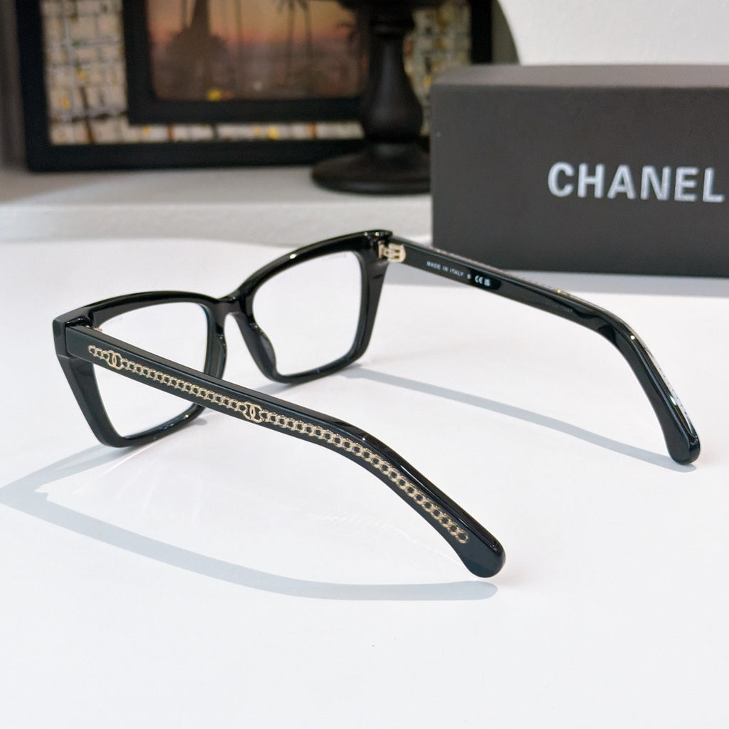 Black square eyeglasses with clear lenses and gold-toned chain trim