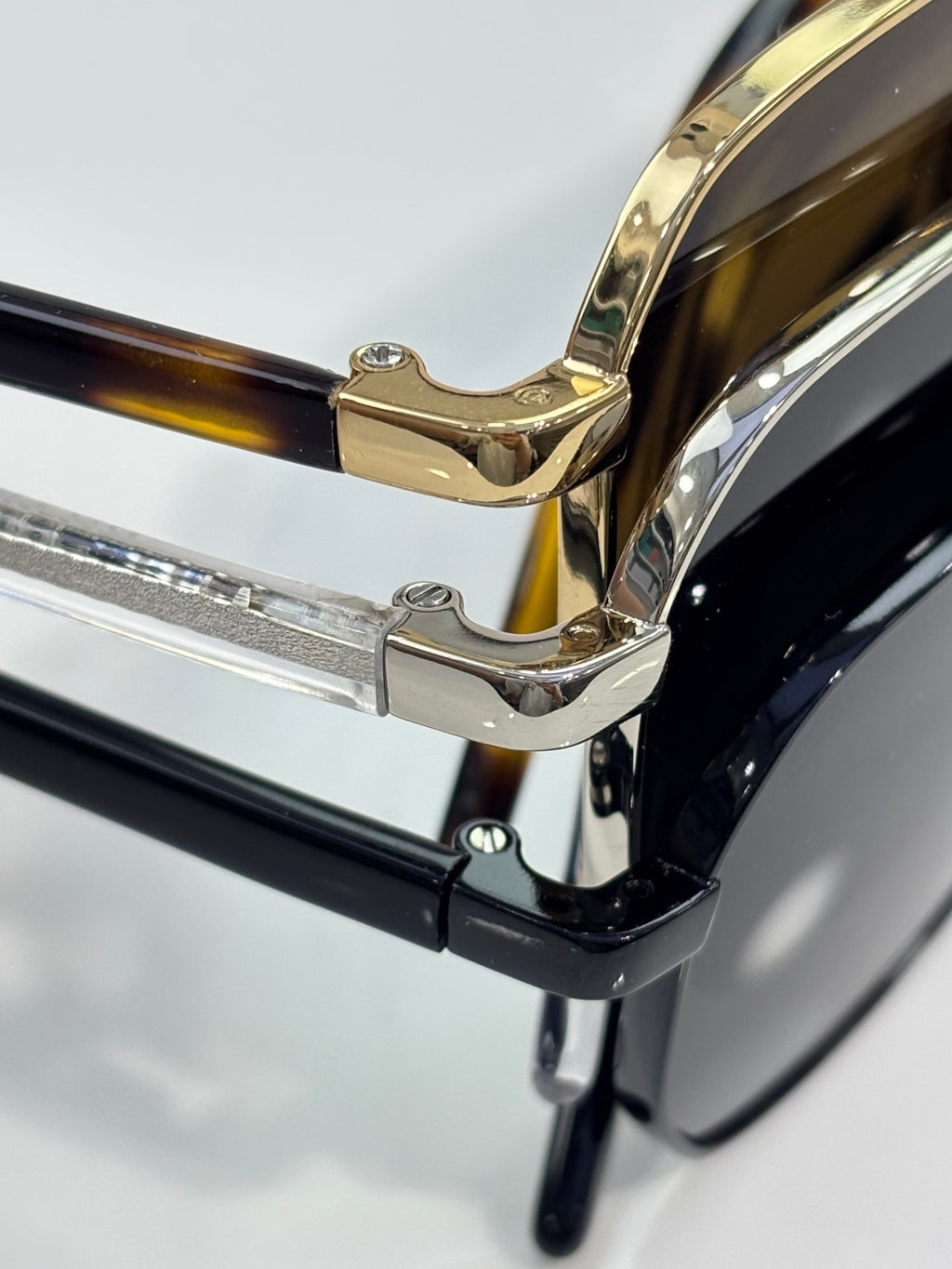 Close-up hinge of black and gold eyeglasses with metal temple