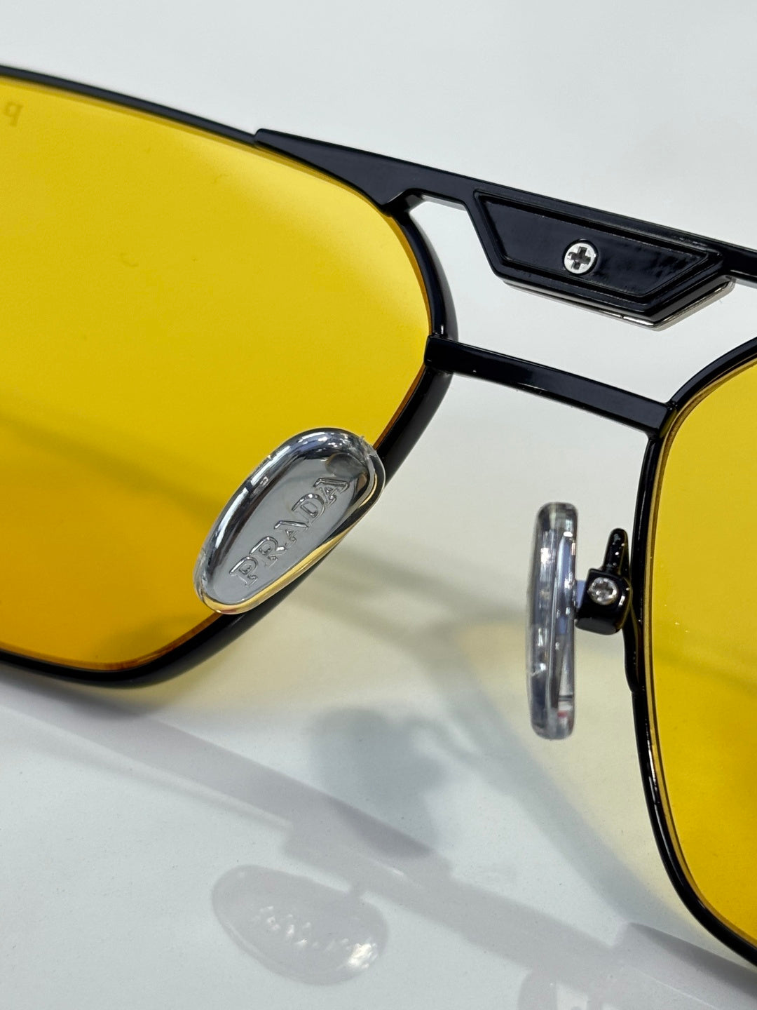 Close-up of yellow lenses with black eyeglass frame and logo detail