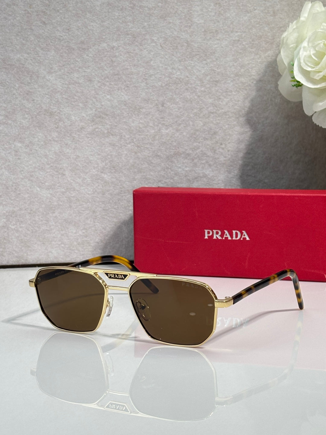 Gold and tortoise sunglasses with rectangular frames and dark lenses